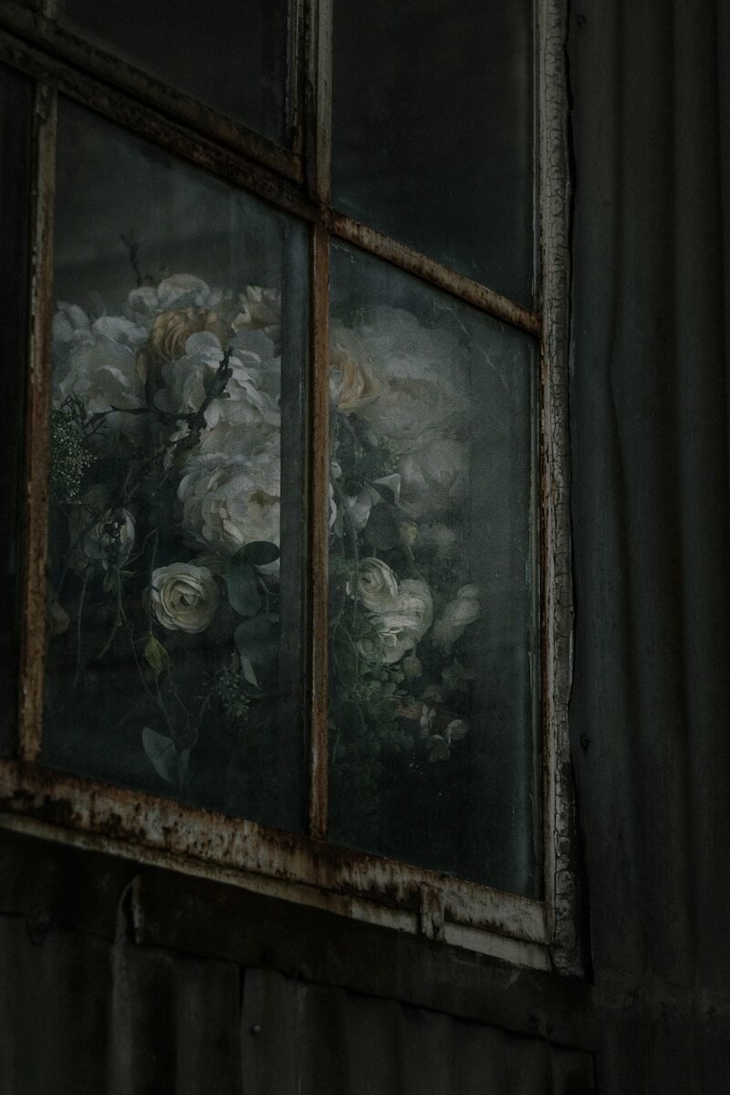 Bouquet of white roses seen through a dusty window.